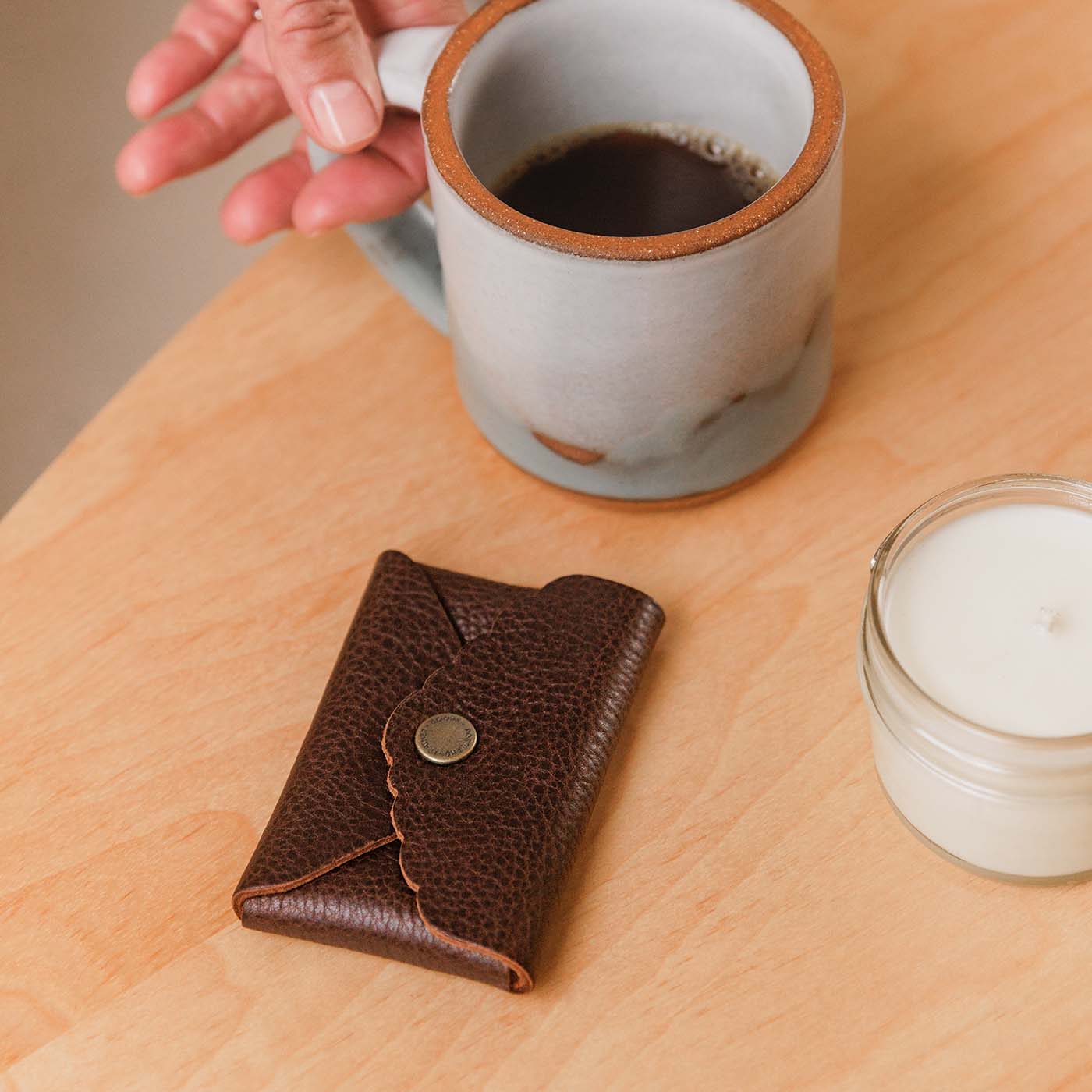Small leather wallet with scalloped edge next to coffee mug