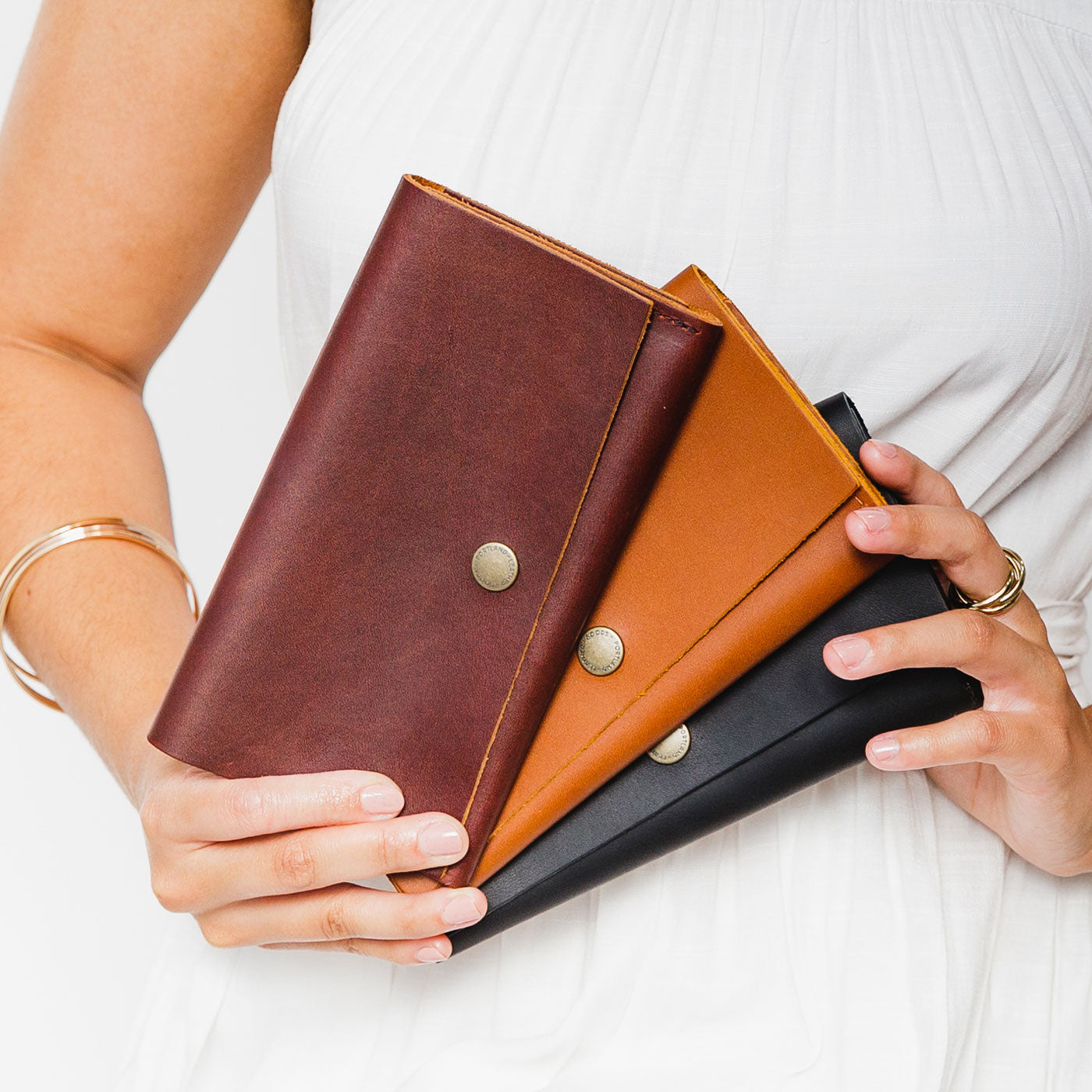 All Variants | Model holding three leather wallets with snap closures
