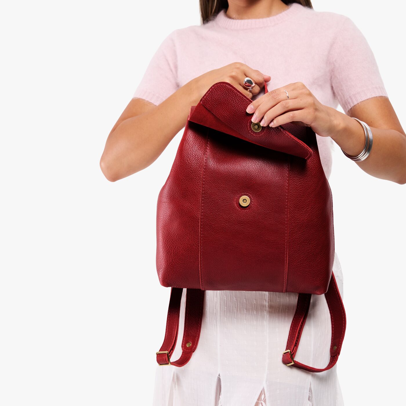 Chili Red | Model holding a leather backpack on a white background