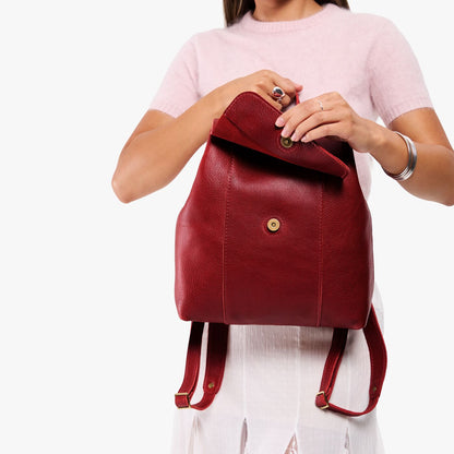 Chili Red | Model holding a leather backpack on a white background