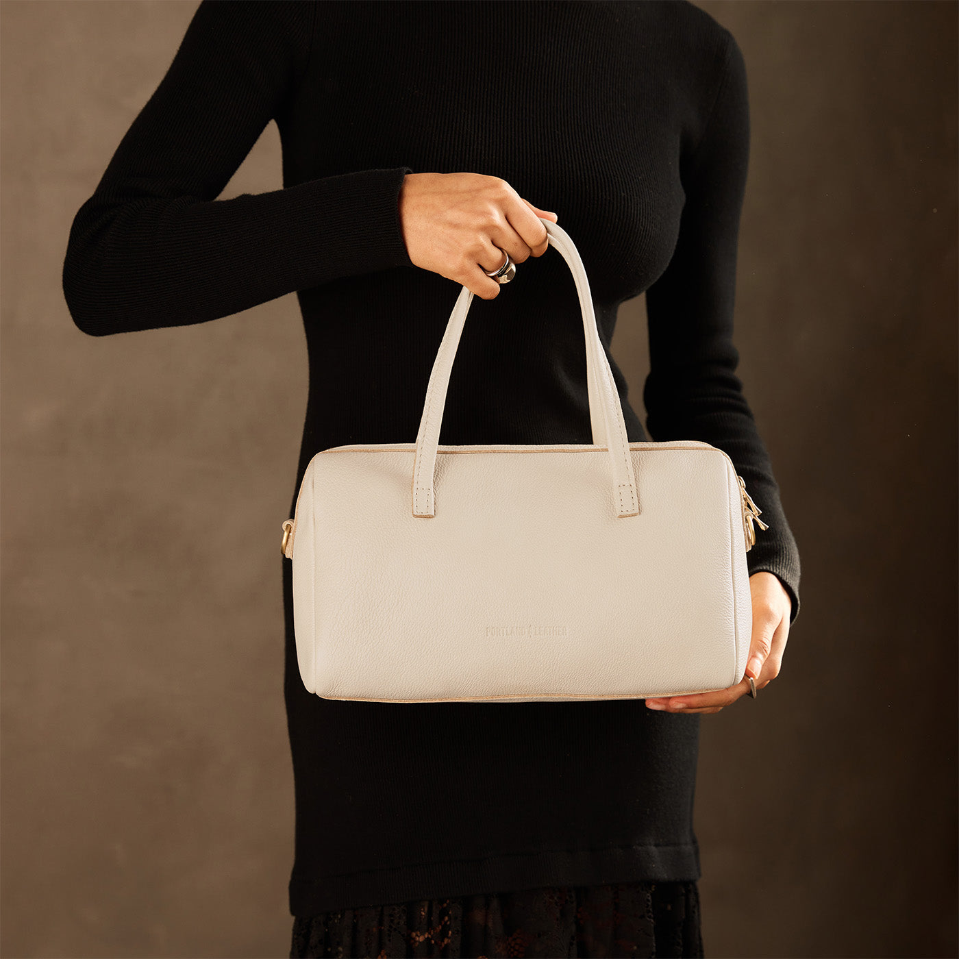 Pebbled Bone*Oversized | Model holding mini duffle shaped handbag with crossbody strap