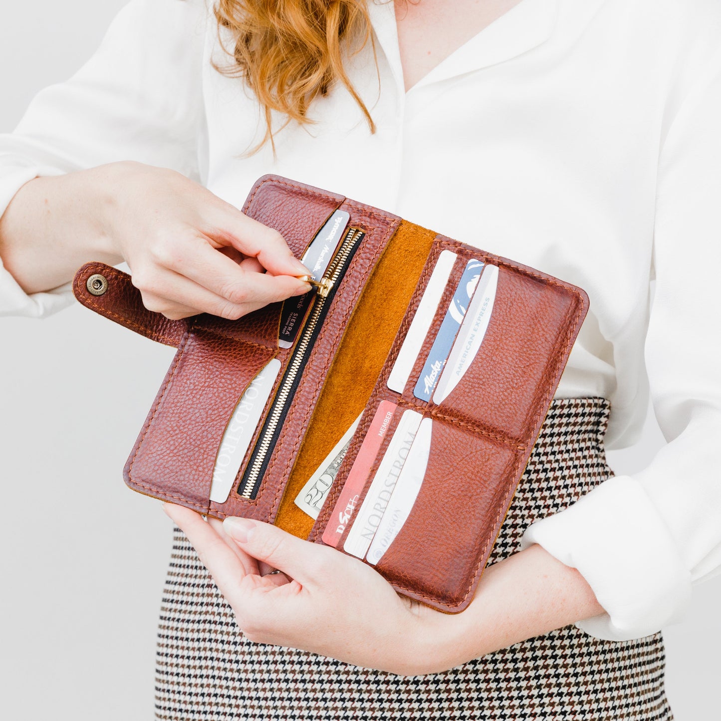 Nutmeg | Model holding flowers and leather wallet with snap open