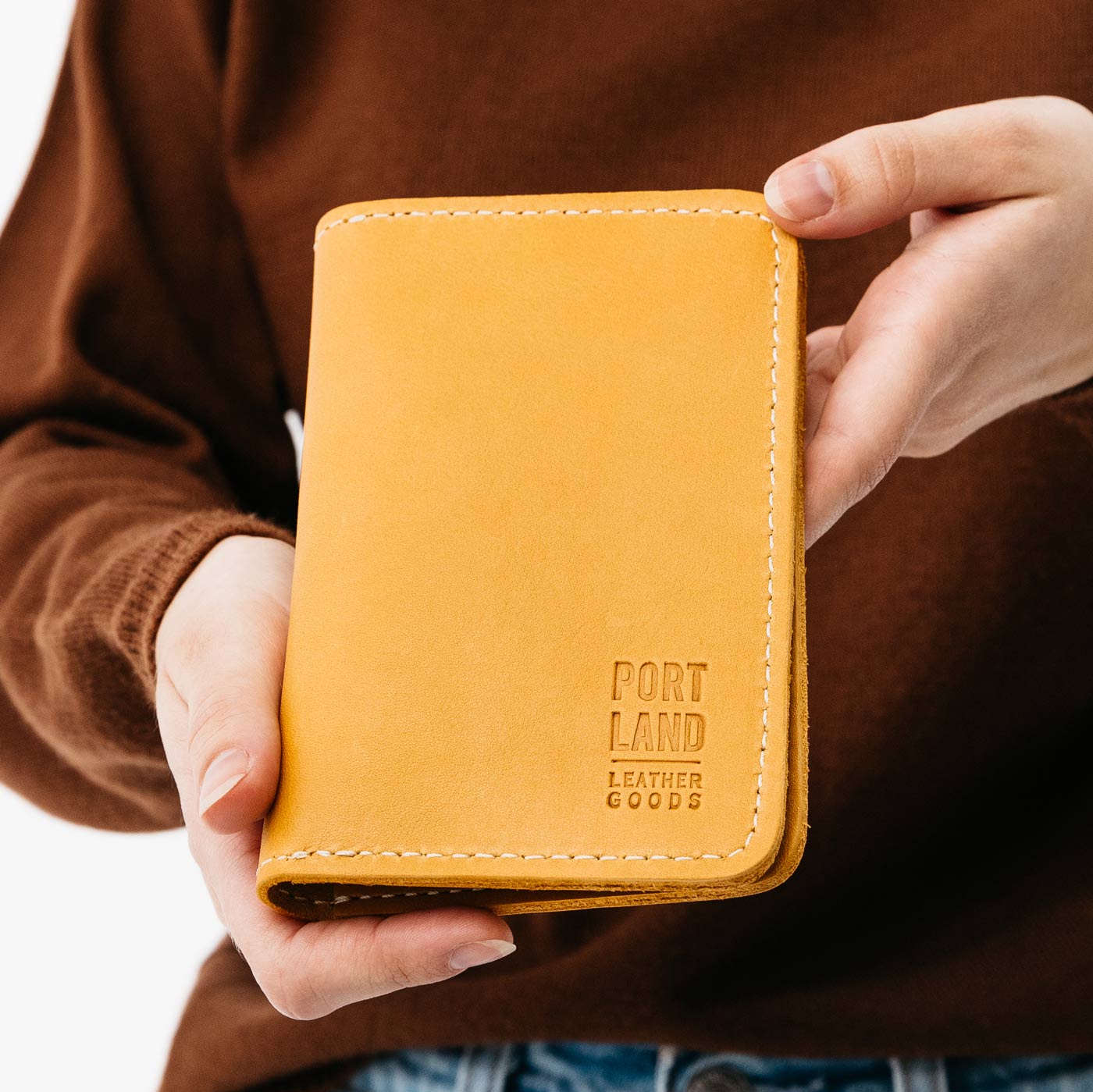 Snflower | Model holding leather passport case with PLG logo