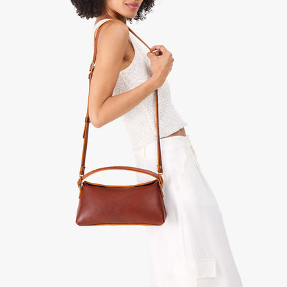 Nutmeg | Model holding a brown colored bowler style hand bag