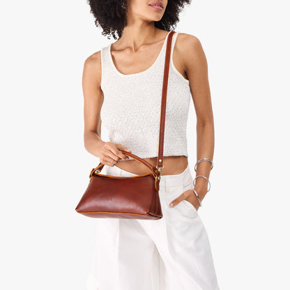 Nutmeg | Model holding a brown colored bowler style hand bag