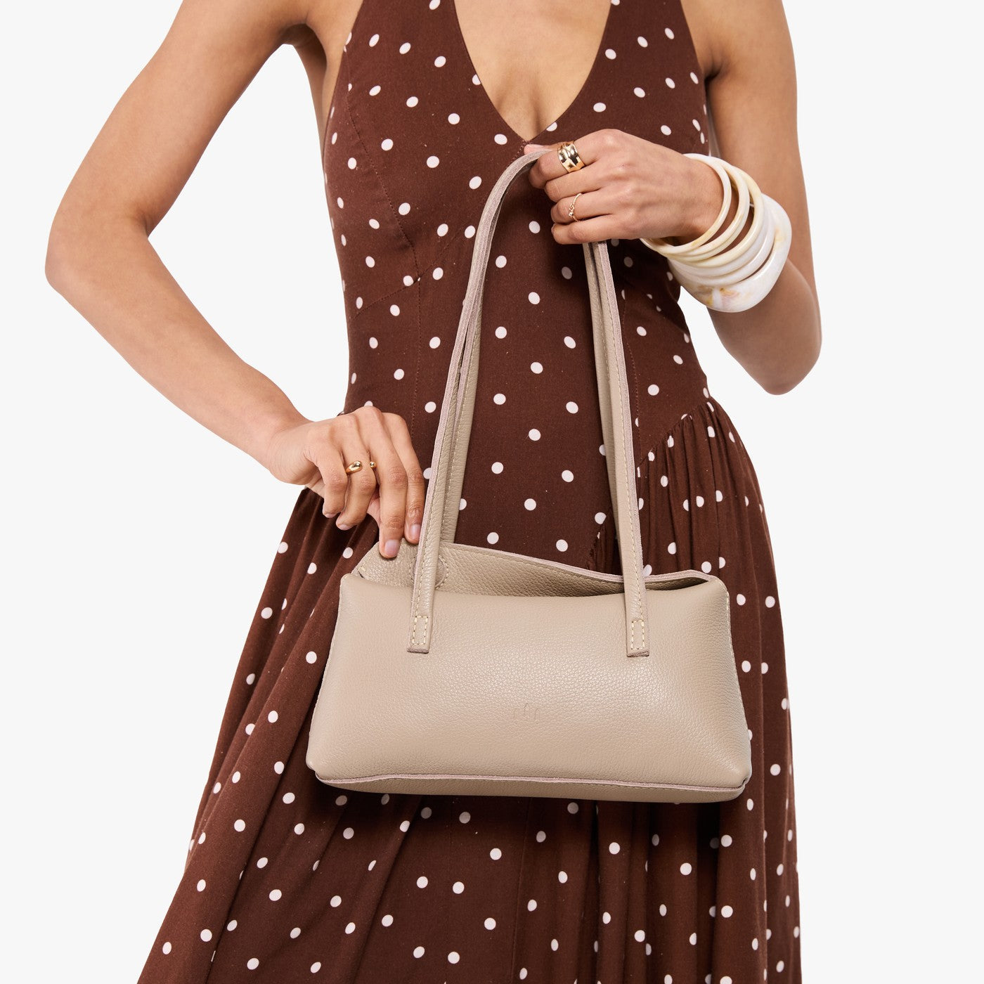 Oatmilk | Model wearing brown dress with white polka dots holding leather bowler bag with magnetic closure
