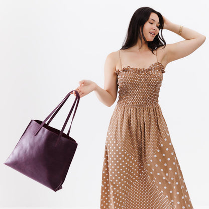 Plum*Large | Model holding leather tote bag with interior snap key loop