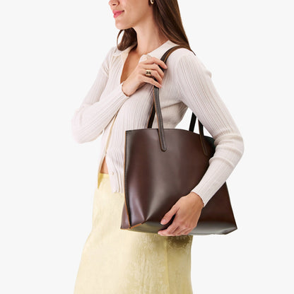 Chocolate Brown*Medium | Model holding leather tote bag with interior snap key loop
