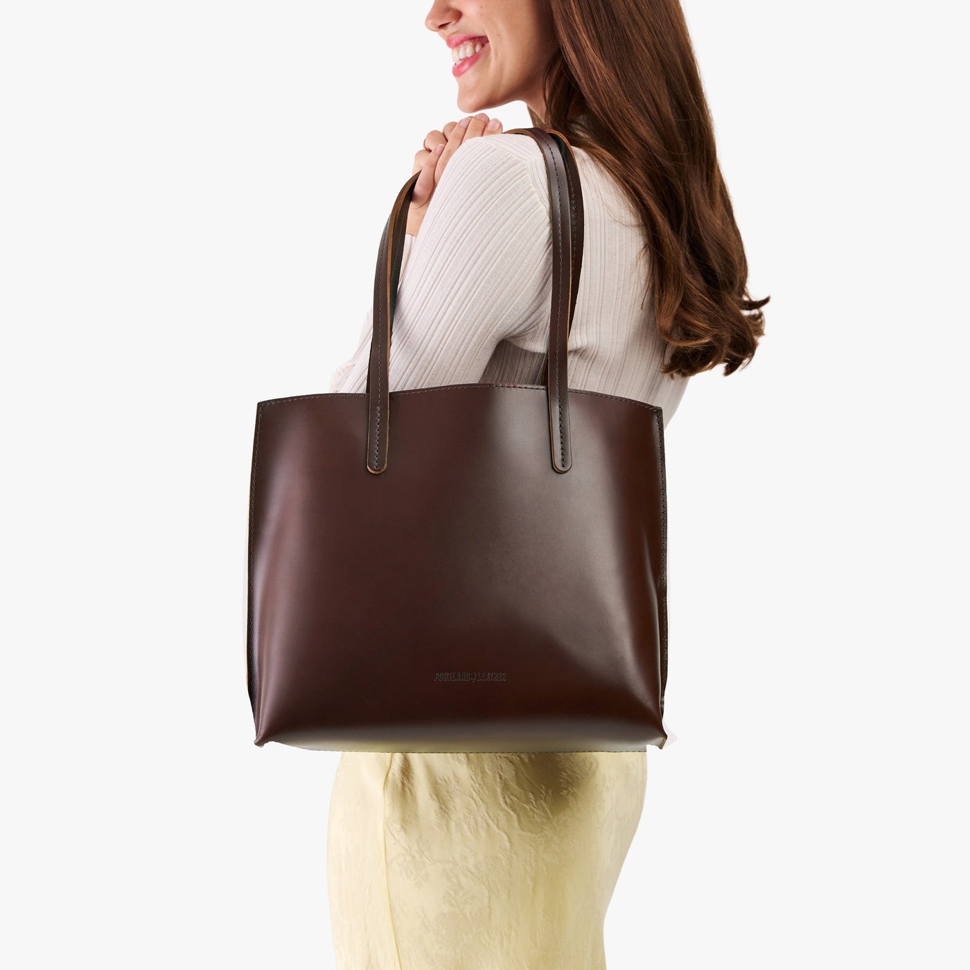 Chocolate Brown*Medium | Model holding leather tote bag with interior snap key loop