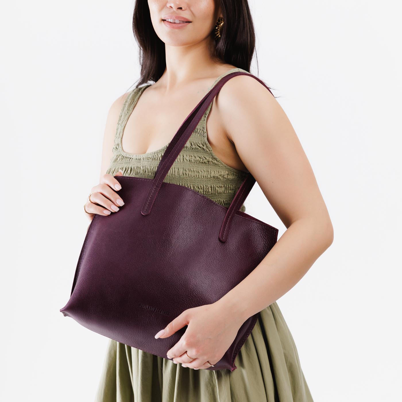 Plum*Medium | Model holding leather tote bag with interior snap key loop