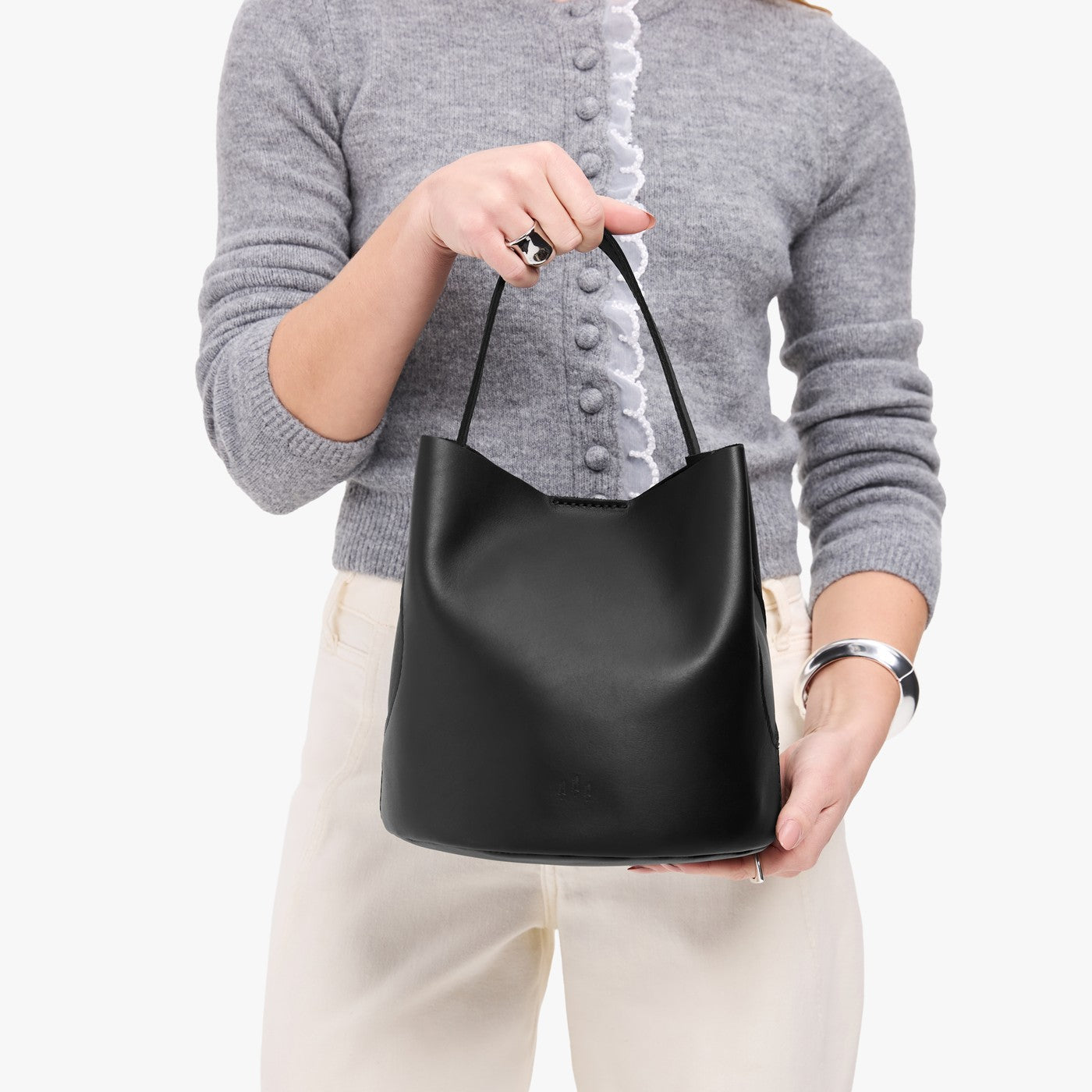 Black*Large | Model holding symmetrical bucket bag with handle, latch closure, and removable crossbody strap
