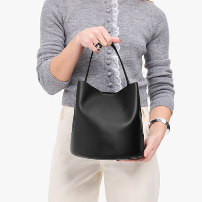 Black*Large | Model holding symmetrical bucket bag with handle, latch closure, and removable crossbody strap