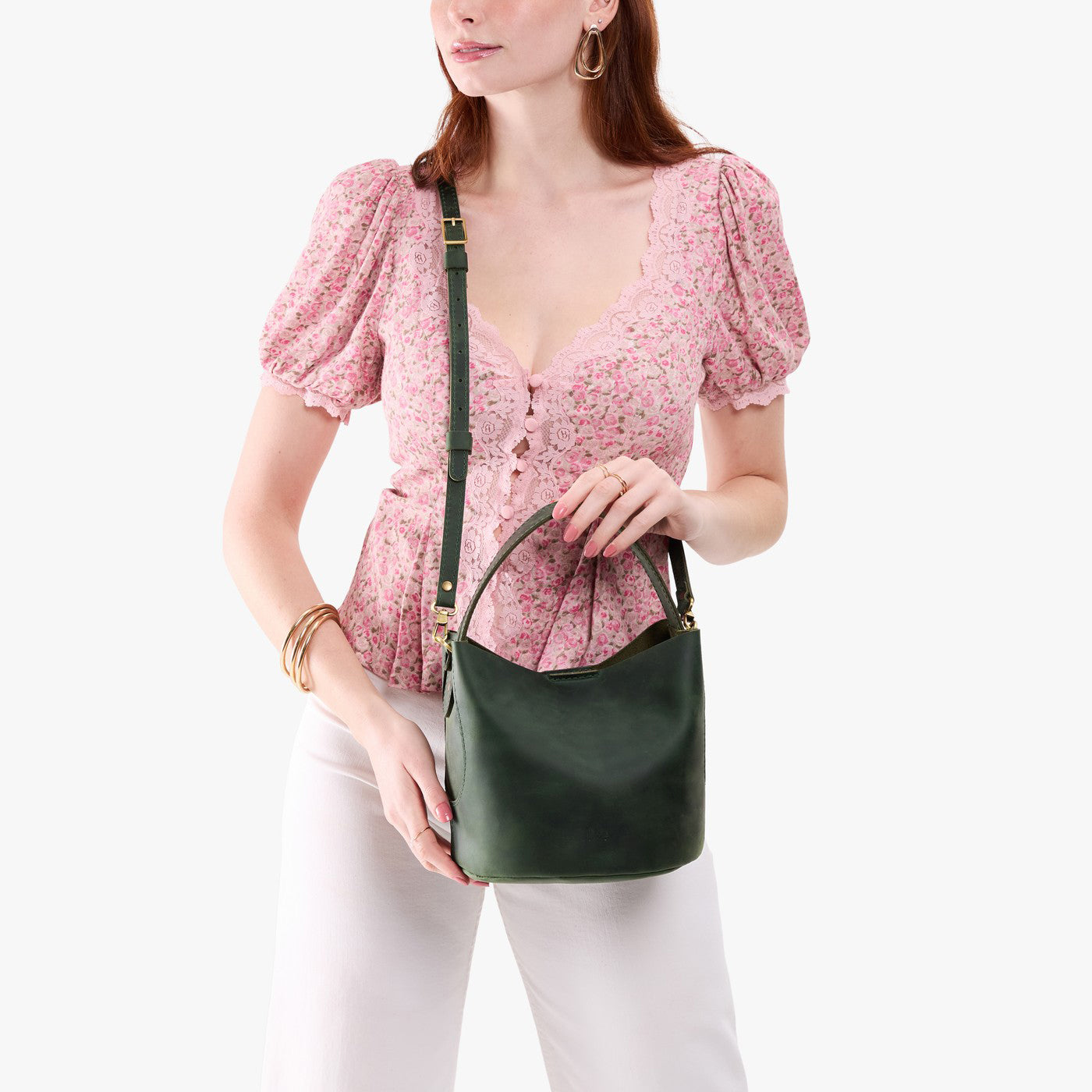 Evergreen*Small | Model holding symmetrical bucket bag with handle, latch closure, and removable crossbody strap