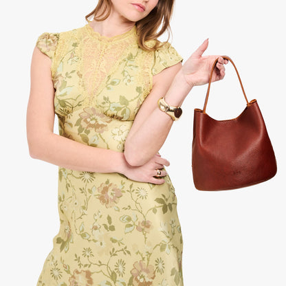 Nutmeg*Small | Model holding symmetrical bucket bag with handle, latch closure, and removable crossbody strap