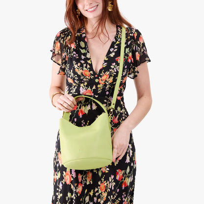 Shadow Lime*Small | Model holding symmetrical bucket bag with handle, latch closure, and removable crossbody strap