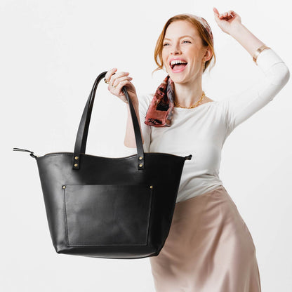 Black*Zipper | Model holding large zipper leather tote bag with sturdy bridle handles and front pocket