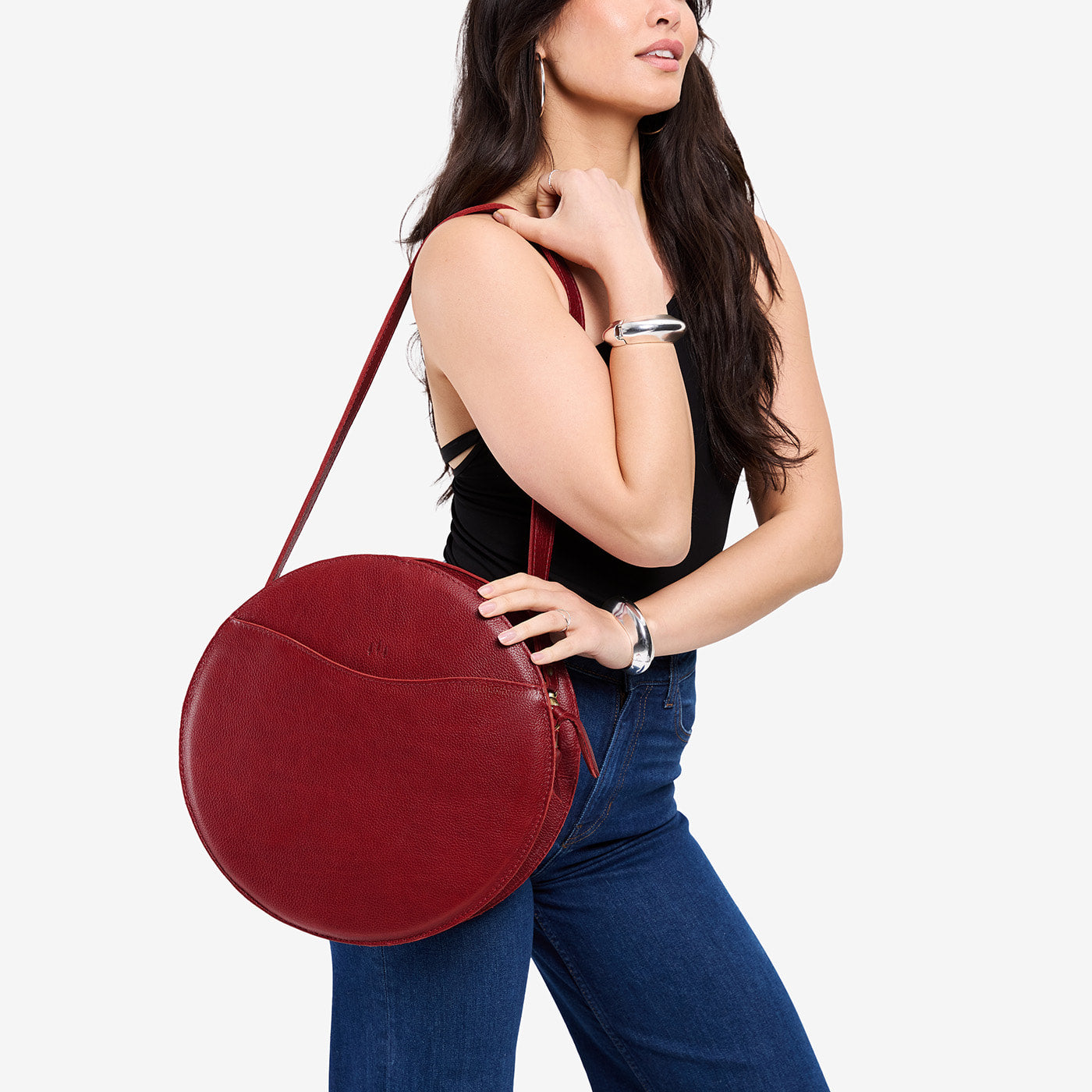 Chili Red | Model carrying large circle shaped leather bag with top zipper and carrying strap