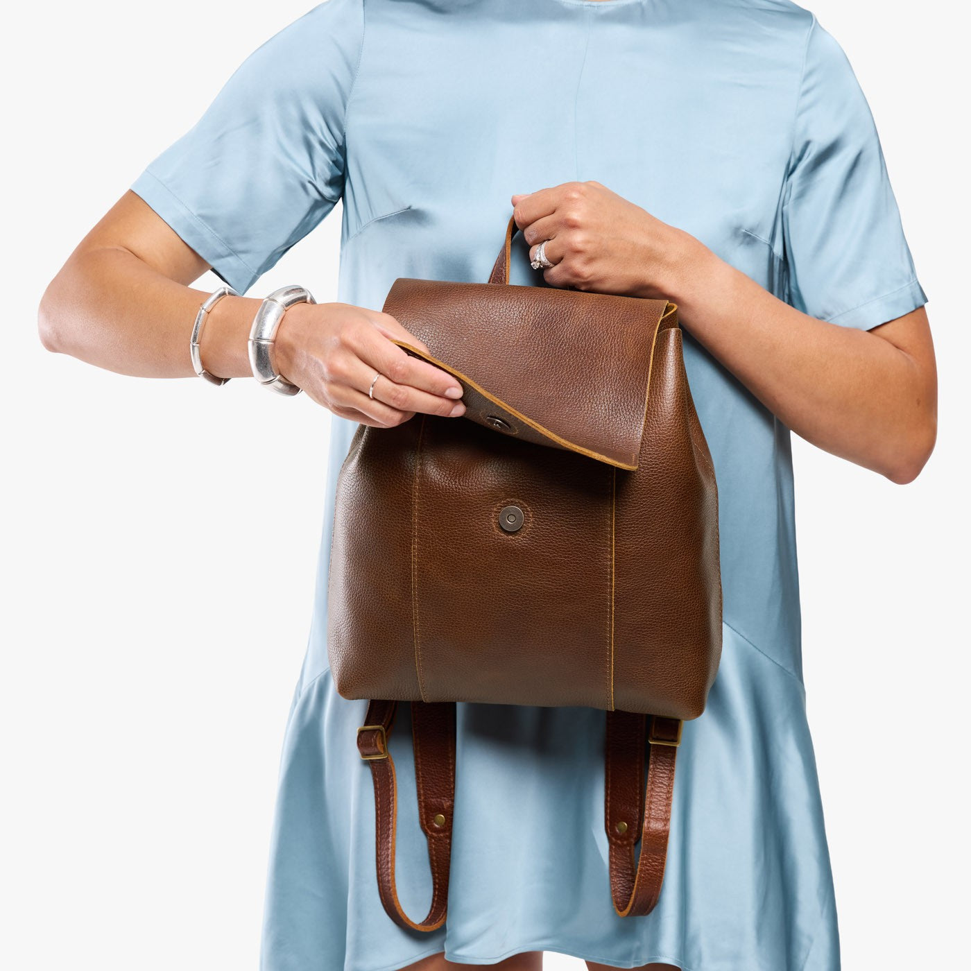 Asheville | Model holding a leather backpack on a white background