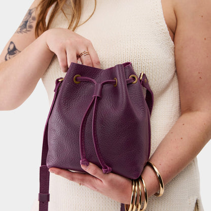Plum*Small | Model holding slouchy crossbody bag with drawstring closure