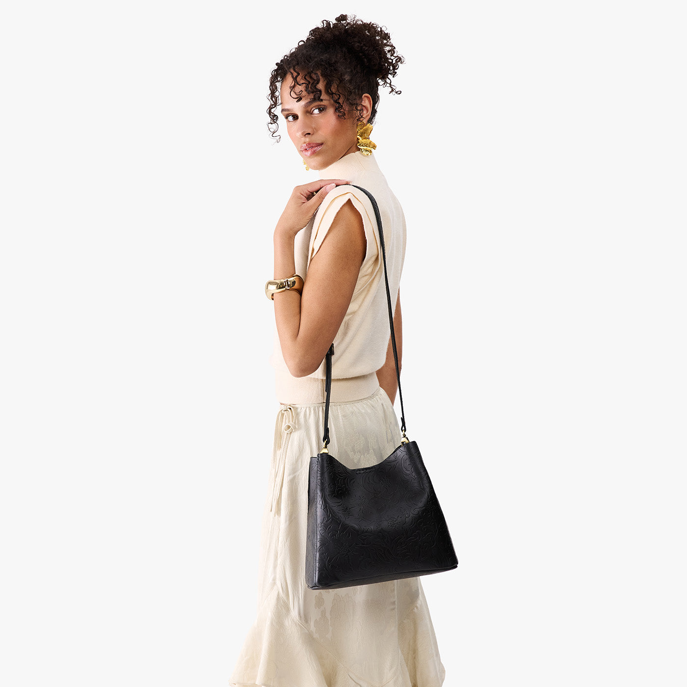 Dahlia | Model wearing symmetrical bucket bag with latch closure and removable crossbody strap