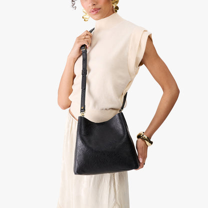 Dahlia | Model wearing symmetrical bucket bag with latch closure and removable crossbody strap
