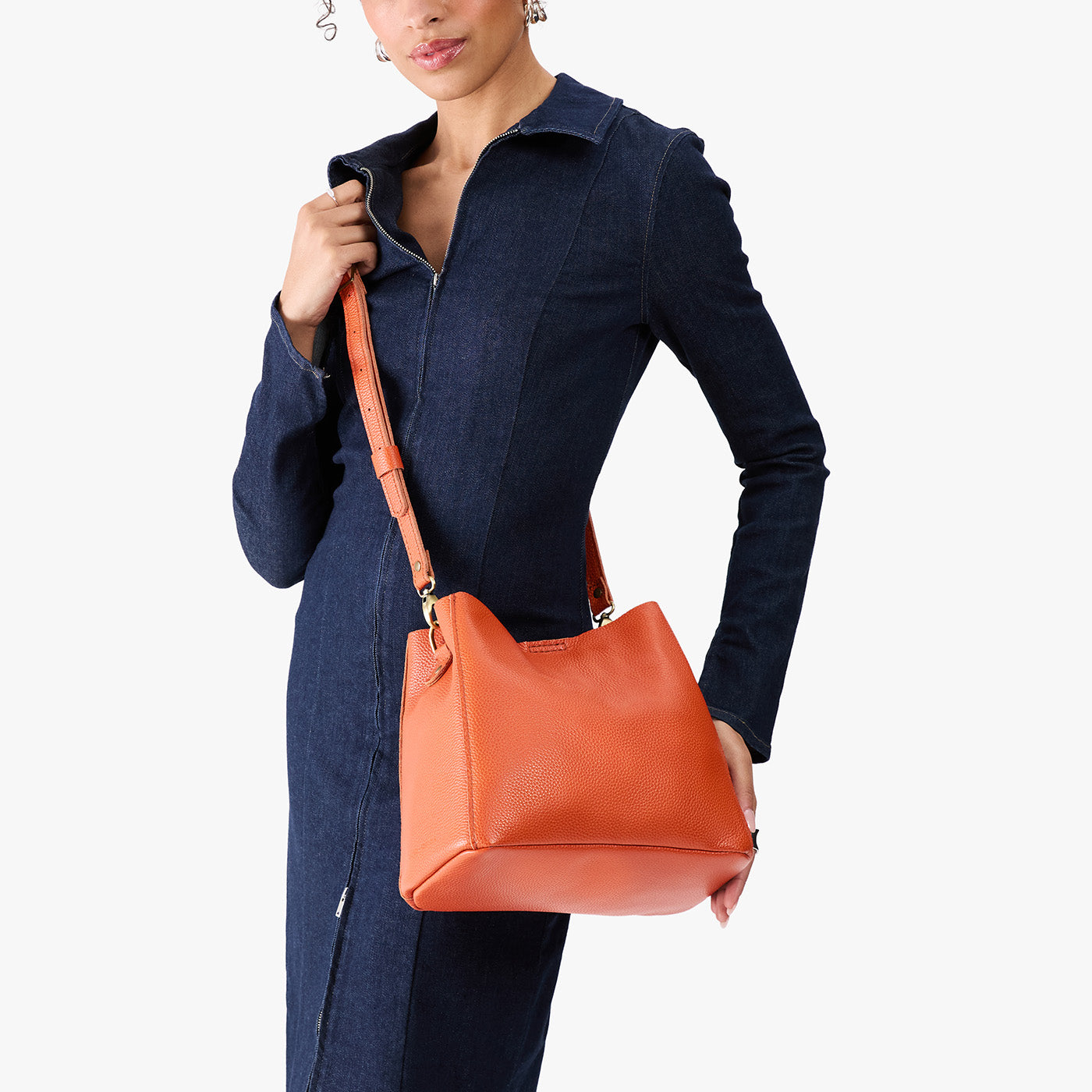 Koi | Model wearing symmetrical bucket bag with latch closure and removable crossbody strap