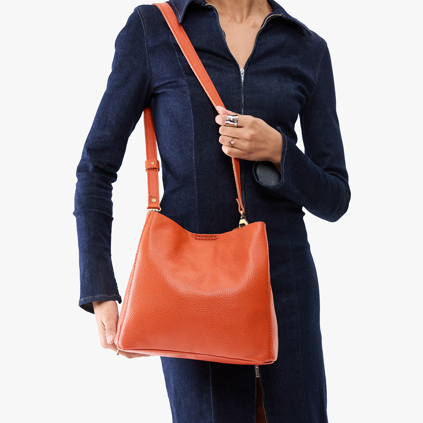 Koi | Model wearing symmetrical bucket bag with latch closure and removable crossbody strap
