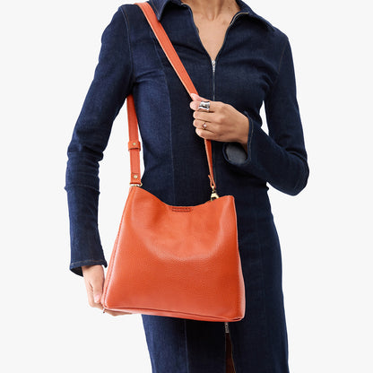 Koi | Model wearing symmetrical bucket bag with latch closure and removable crossbody strap