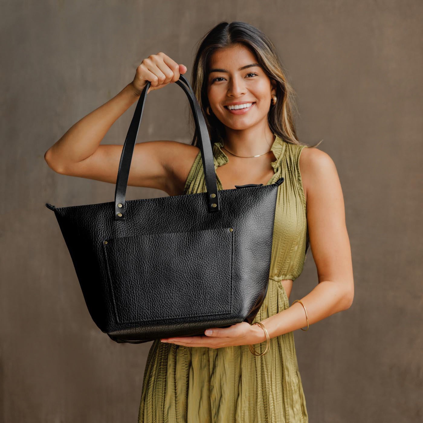 Pebbled--black*Zipper | Model holding large zipper leather tote bag with sturdy bridle handles and front pocket