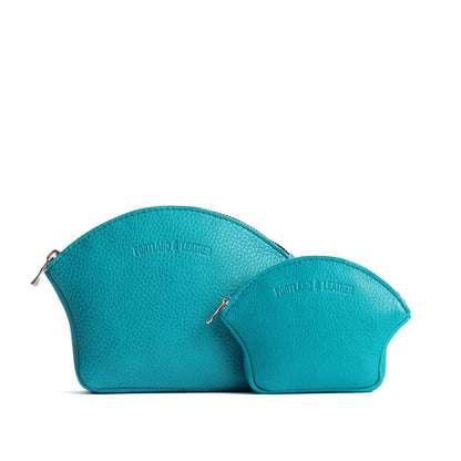 Baja | Comparison shot of small and large seashell shaped leather makeup bags with curved top zipper and flat bottom