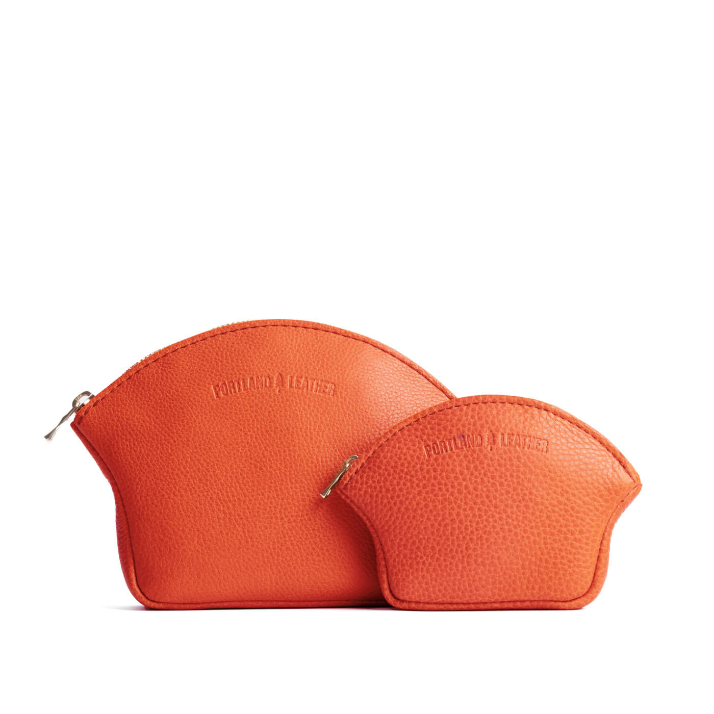 Koi | Comparison shot of small and large seashell shaped leather makeup bags with curved top zipper and flat bottom