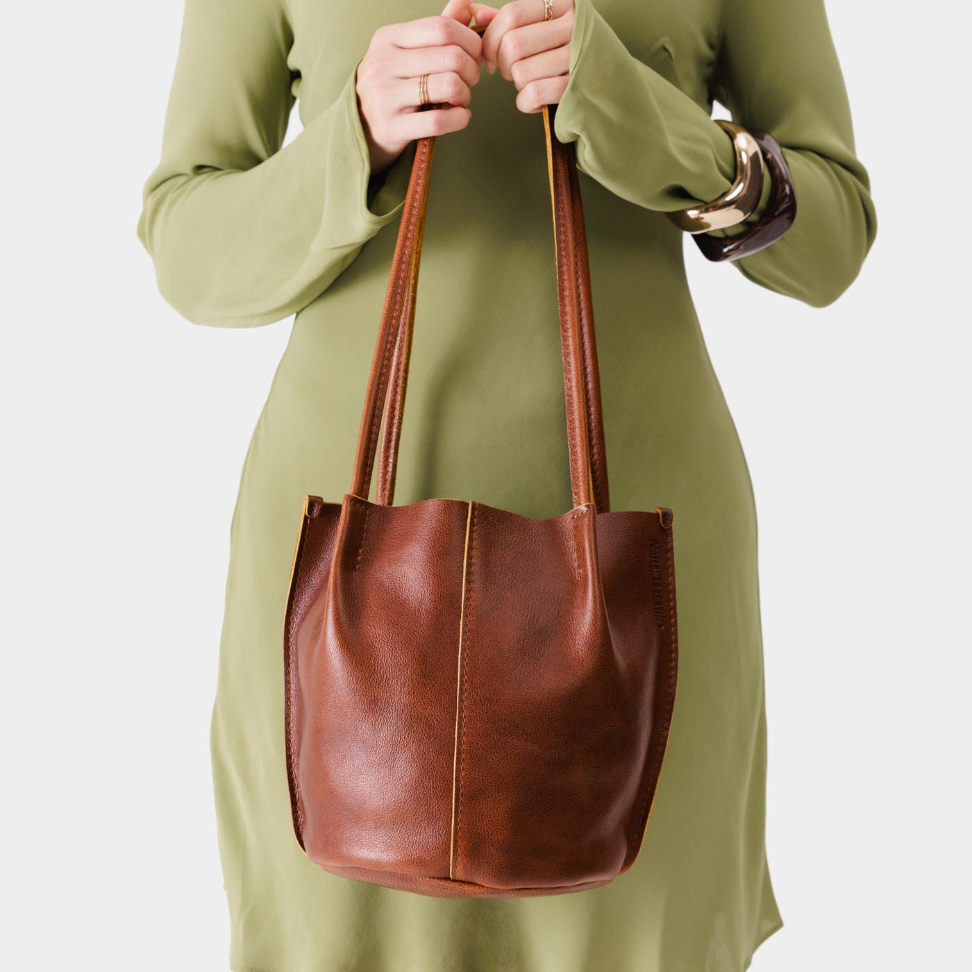 Nutmeg*Small | Model wearing light green dress holding petite bucket shaped tote bag with matching leather handles