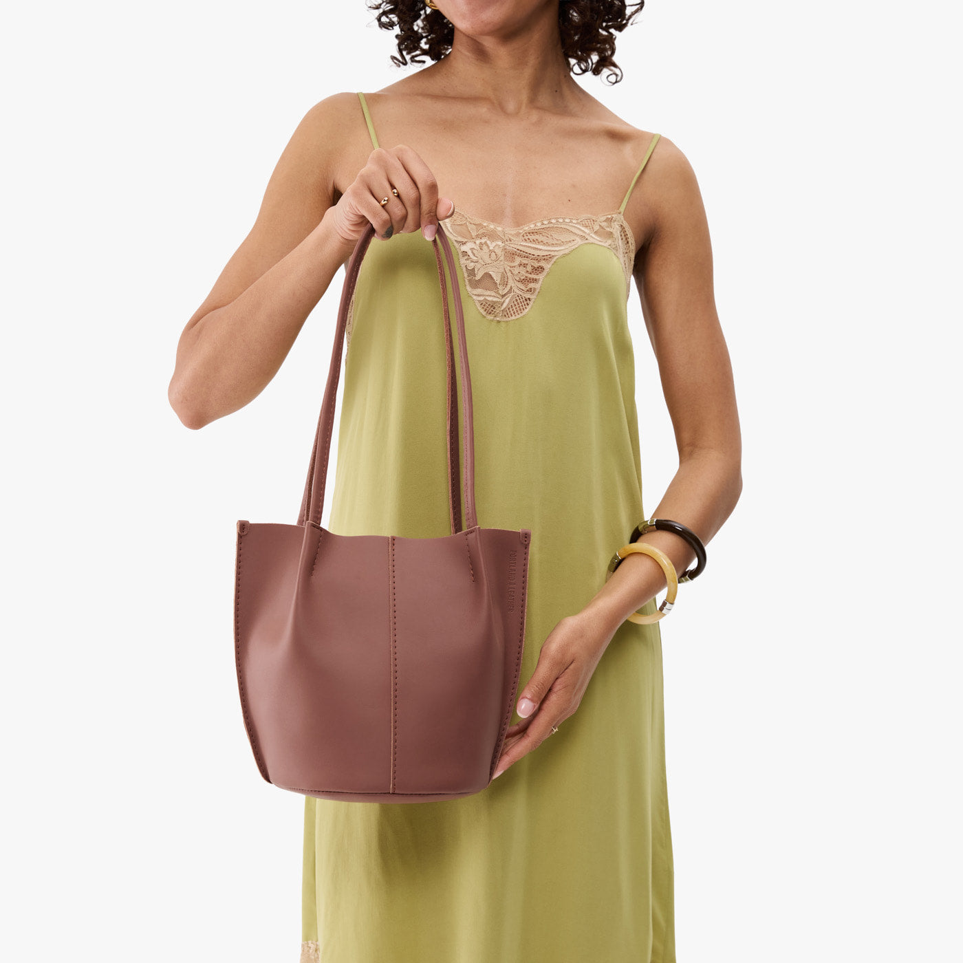 Sunkissed*Small | Model wearing sleeveless light green dress holding petite bucket shaped tote bag with matching leather handles