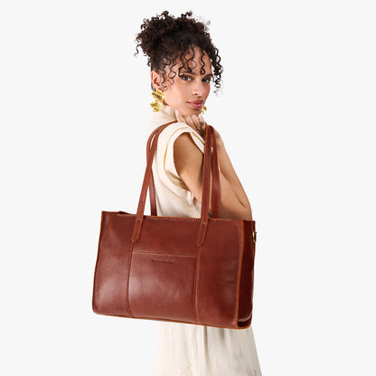Nutmeg*Oversized East/West | Model holding structured wide tote bag with overlapping panels and crossbody strap