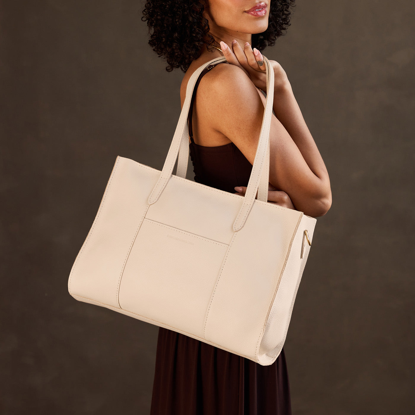 Pebbled Bone*Oversized East/West | Model holding structured wide tote bag with overlapping panels and crossbody strap