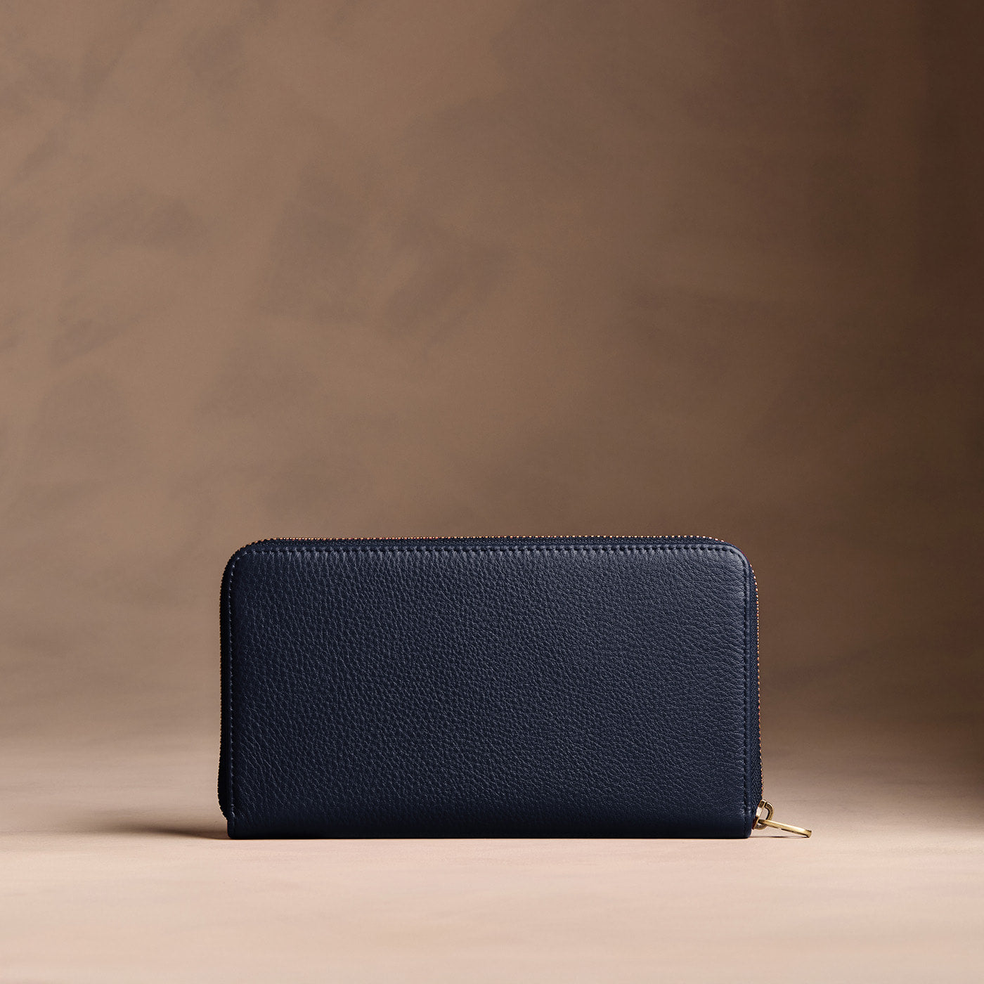 Anchor Blue | Full zip around wallet with a strap on a brown background