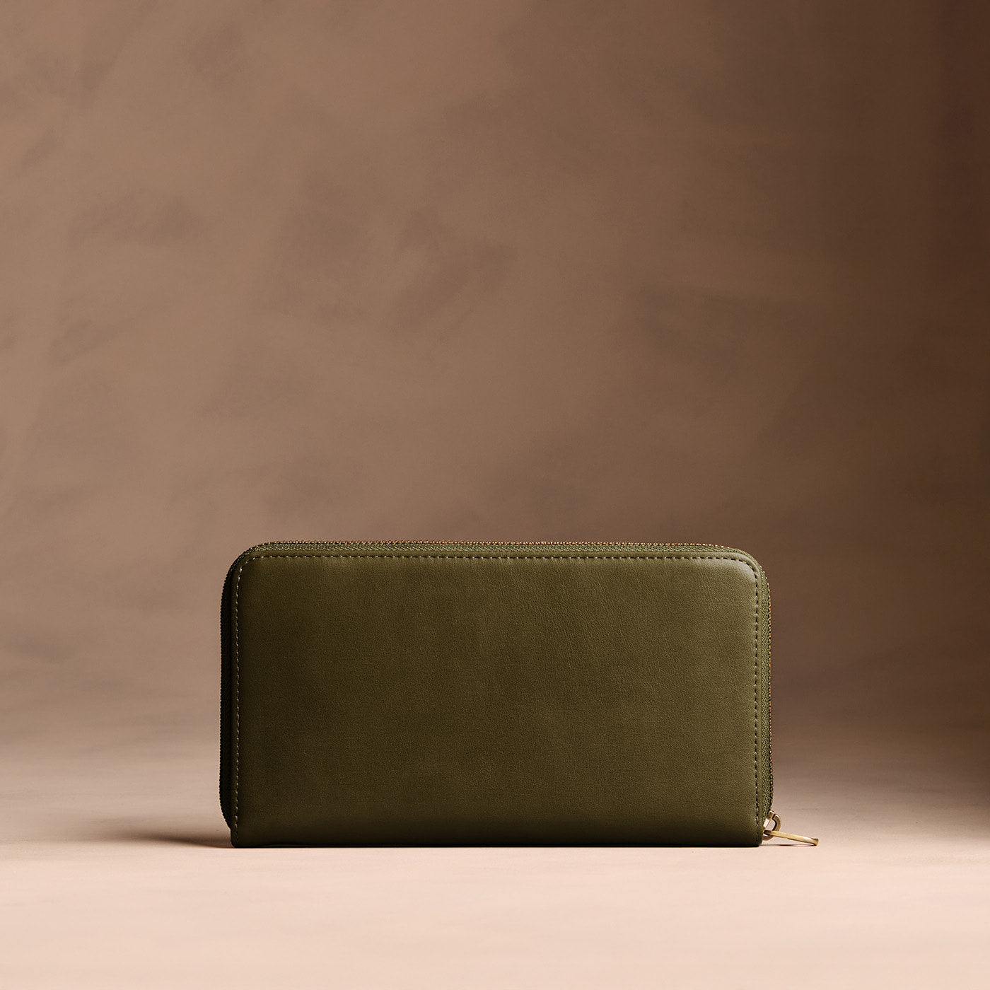 Bay Green | Full zip around wallet with a strap on a brown background
