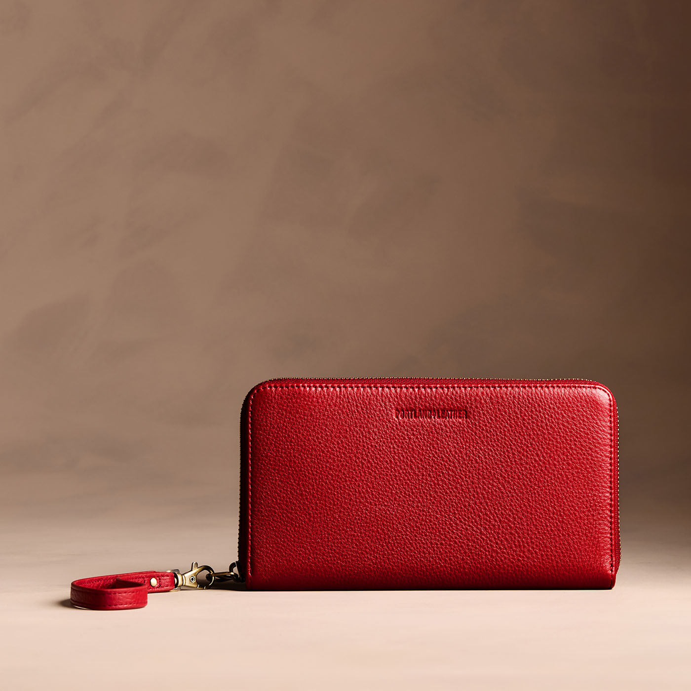 Icon Red | Full zip around wallet with a strap on a brown background