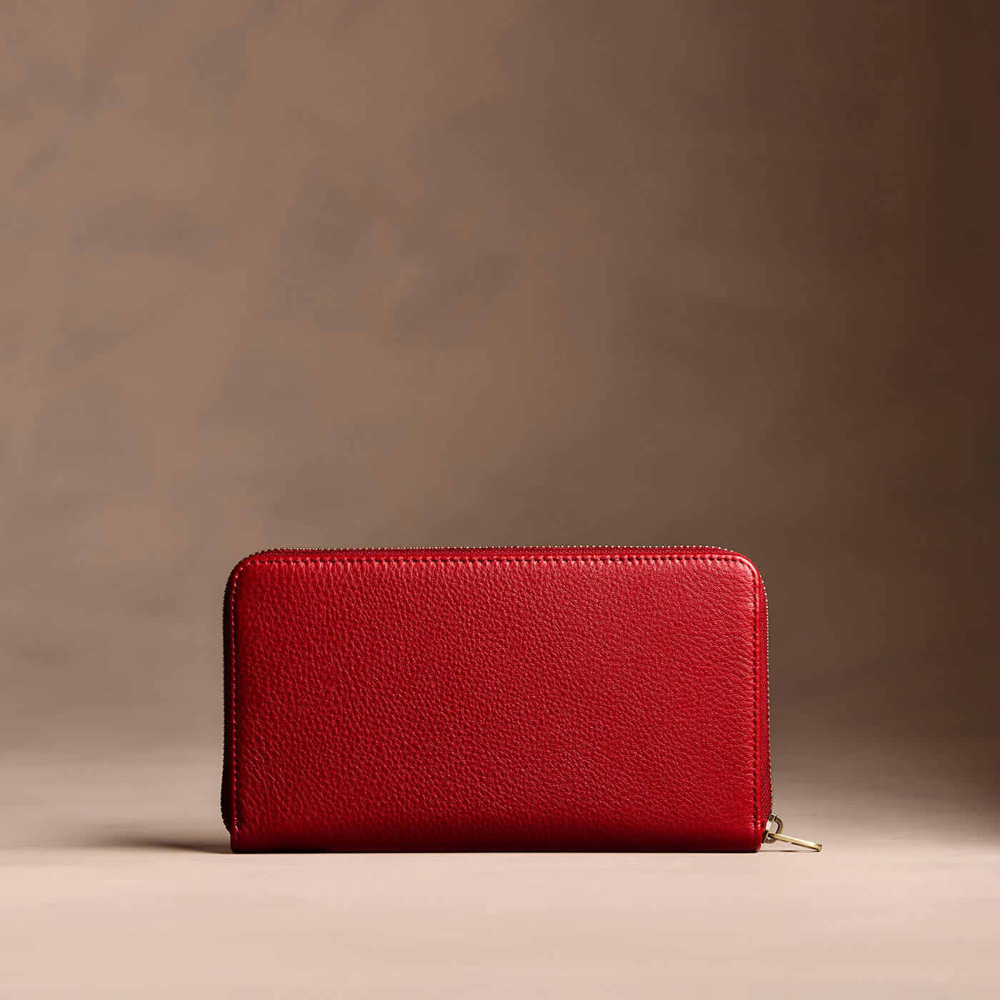 Icon Red | Full zip around wallet with a strap on a brown background