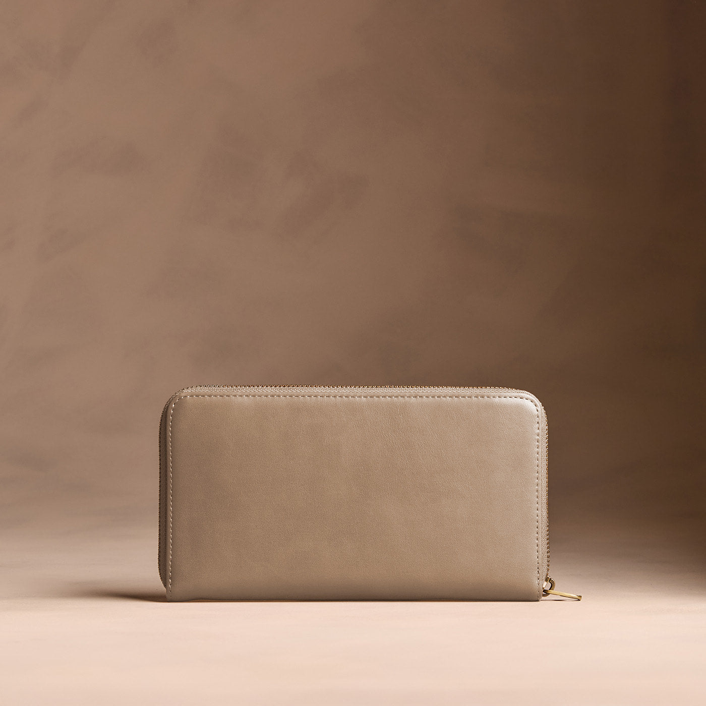 Satine | Full zip around wallet with a strap on a brown background