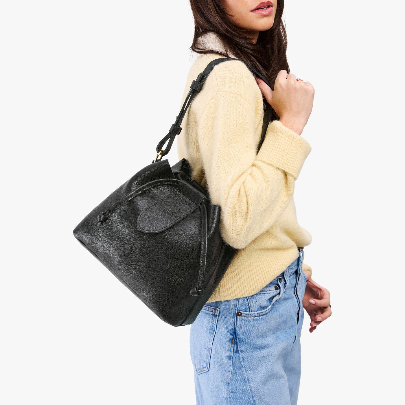 Pebbled--black*Large | Model wearing symmetrical leather bag with leather drawstring closure and adjustable shoulder strap