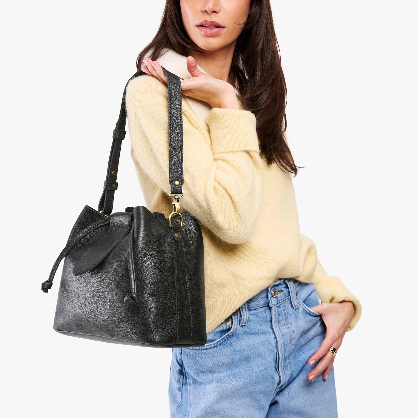 Pebbled--black*Large | Model holding symmetrical leather bag with leather drawstring closure and adjustable shoulder strap