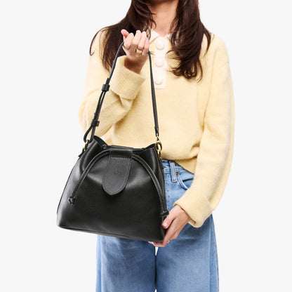 Pebbled--black*Large | Model holding symmetrical leather bag with leather drawstring closure and adjustable shoulder strap