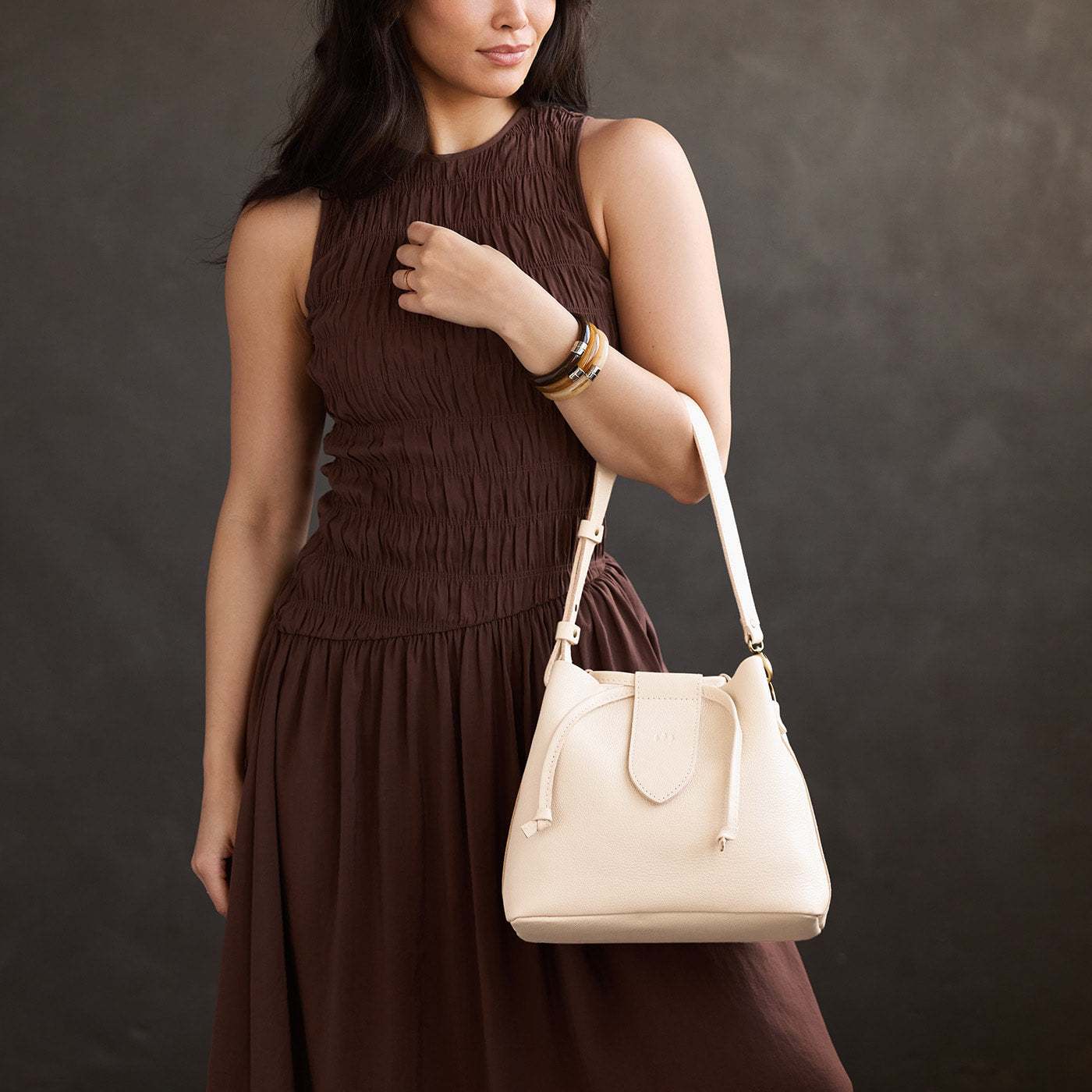 Pebbled Bone*Large | Model holding symmetrical leather bag with leather drawstring closure and adjustable shoulder strap