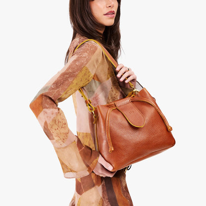 Sienna*Large | Model holding symmetrical leather bag with leather drawstring closure and adjustable shoulder strap