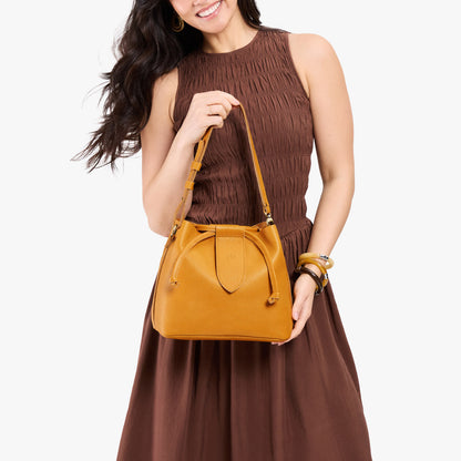 Sunshine*Large | Model holding symmetrical leather bag with leather drawstring closure and adjustable shoulder strap