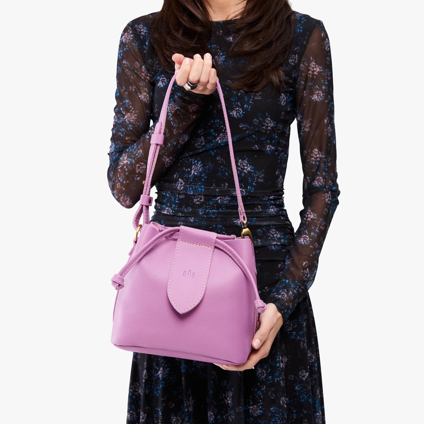 Calla Lily*Small | Model holding symmetrical leather bag with leather drawstring closure and adjustable shoulder strap