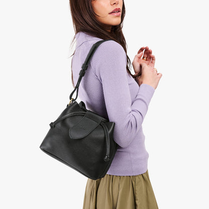 Pebbled--black*Small | Model wearing symmetrical leather bag with leather drawstring closure and adjustable shoulder strap