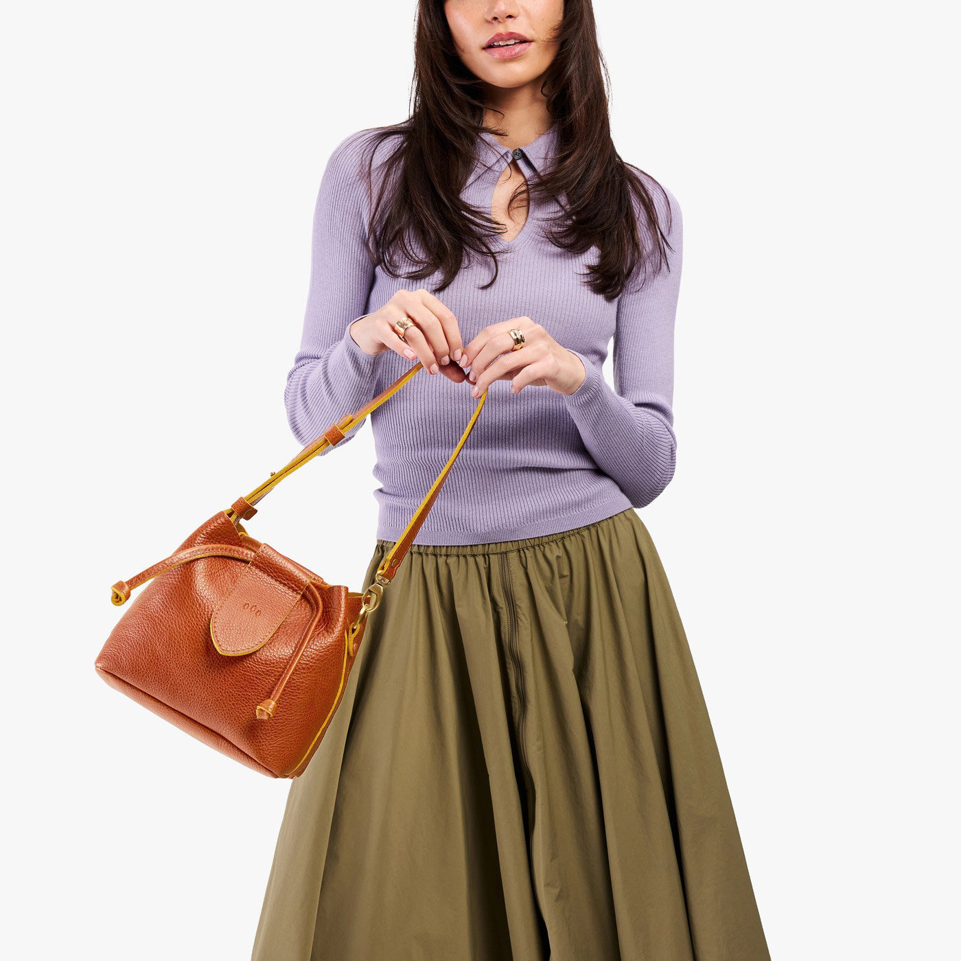 Sienna*Small | Model holding symmetrical leather bag with leather drawstring closure and adjustable shoulder strap