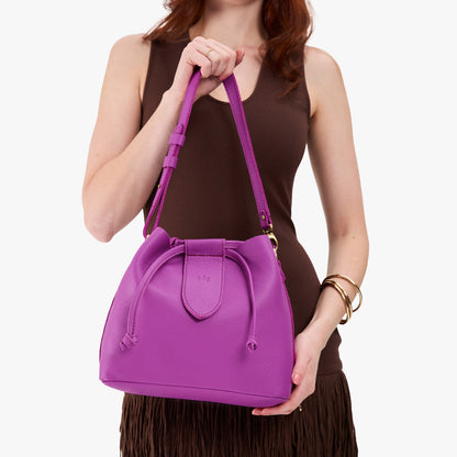 Cattleya*Large | Model holding symmetrical leather bag with leather drawstring closure and adjustable shoulder strap
